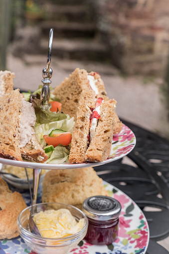 A cake stand full of finger sandwiches, delicious scones, cakes and other fancy treats as part of an English Afternoon in a stately home.