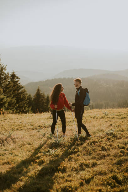 istock Smiling couple walking with backpacks over green hills 1491228659