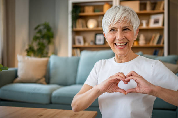 Happy elderly woman making a heart sign with her hands stock photo