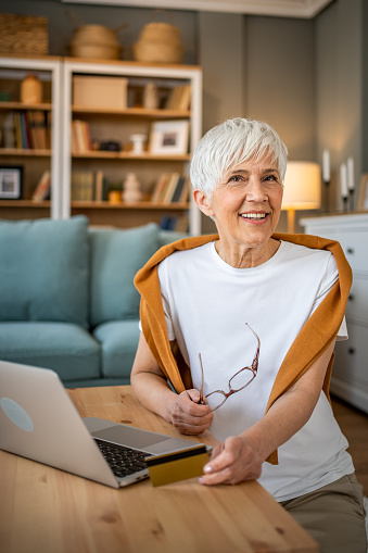 Portrait of cheerful senior woman using laptop at home