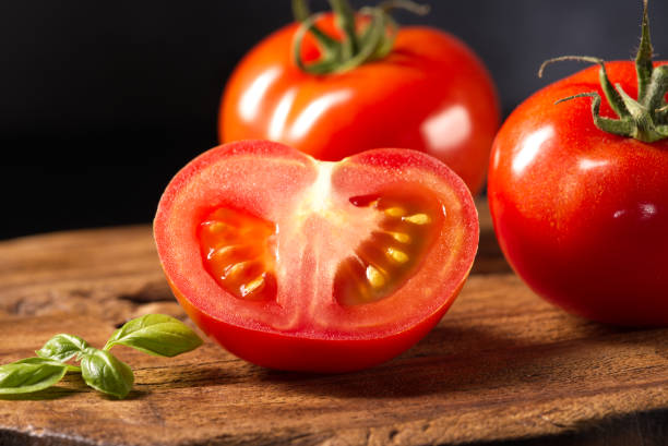 istock Red cut tomato on a wooden board. 1491229685