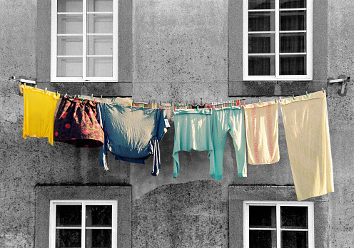 Laundry, multicolored clothes hanging to dry in back yard facade. Windows in the background. Galicia, Spain.