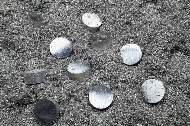 Close-up of a few aluminum pieces placed on aluminum scrap dust waste after machining aluminum scrap on a lathe.