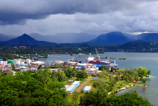 Kolonia, capital of Pohnpei State, Federated States of Micronesia: view of the port of Kolonia from the air, docks, warehouses and fuel storage area (tank farm) - container ship and fishing boats docked - Dekehtik Island, connected by a causeway to Pohnpei - Sokehs Island in the background.