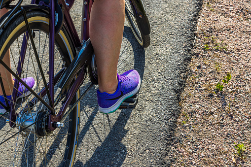Sweden. Uppsala. 05.14.2023. View of woman's foot in Nike sneakers on bicycle pedal.