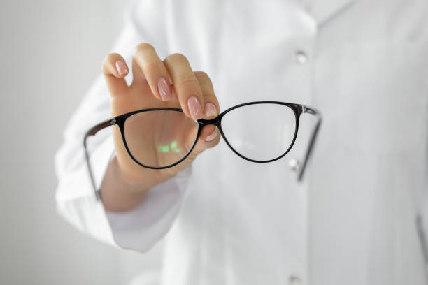 Female optician hands giving new glasses to customer for testing
