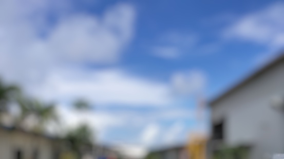 Blur image of cloudy blue sky between buildings looking bright during the day