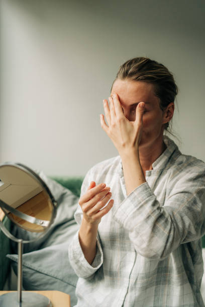 istock A beautiful woman massages her face while sitting in front of a mirror. 1491241372