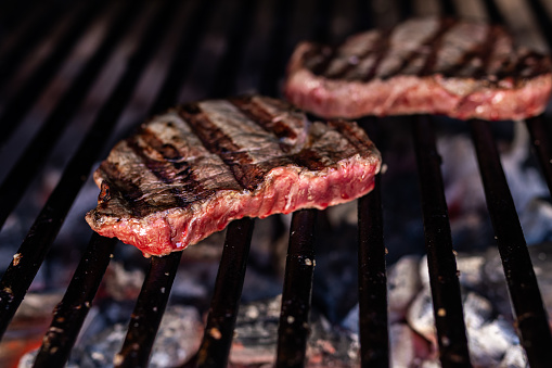 beef steak being grilled over hot coals on a barbecue. ready-to-eat food. food and nutrition concept