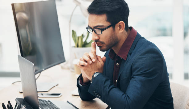 istock Office, brainstorming and man at computer thinking of ideas for online project with serious concentration. Planning, analytics and Indian businessman on web search for startup business idea at desk. 1491242724