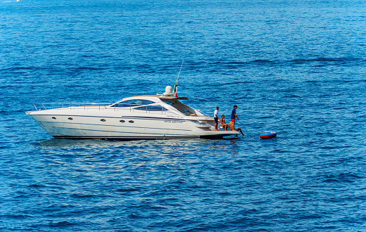 La Spezia, Italy - July 23, 2022: White luxury motor boat anchored in the blue Mediterranean sea with some people aboard on a sunny summer day. Gulf of La Spezia, La Spezia, Liguria, Italy, Europe.