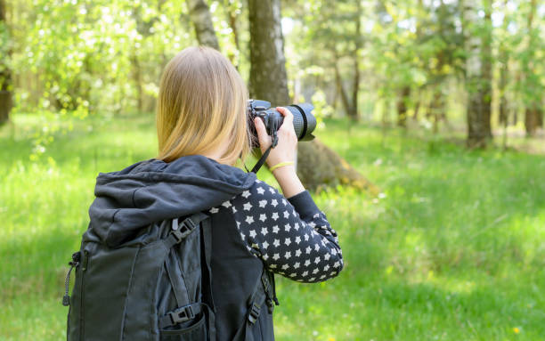 istock Blonde woman in the forest with a backpack and a camera 1491267881