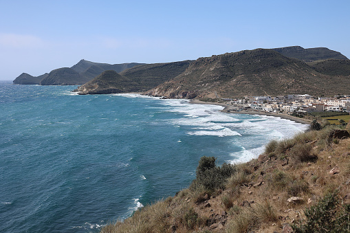 The coastline around the white village of Las Negras seen from the surrounding cliffs.  The waters of the Mediterranean sea are blue.