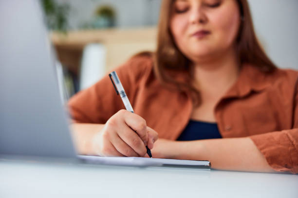 istock A plus-size woman writes notes while working on the laptop at the table. 1491271414