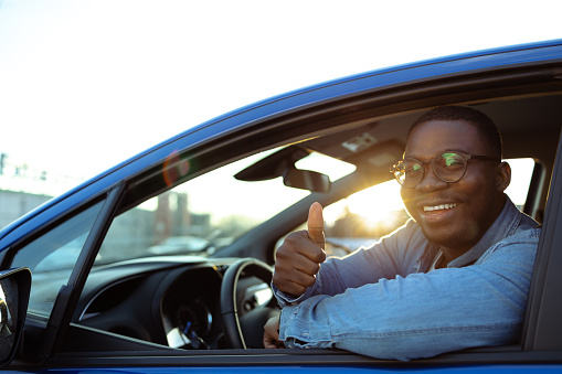 Smiling African-American man holding the steering wheel and smiling while looking at the camera