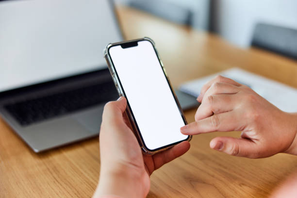 istock A close-up of hands holding a smartphone and touching a blank white screen with a finger. 1491271521