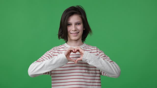 Young boy shows heart shape with hands