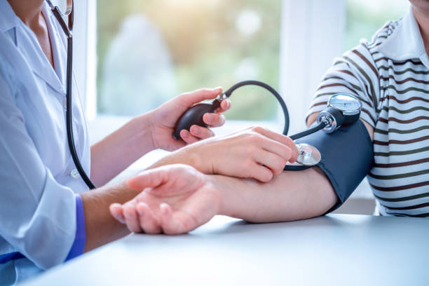 el médico mide la presión del paciente durante un examen médico y una consulta en el hospital - blood pressure bulb fotografías e imágenes de stock