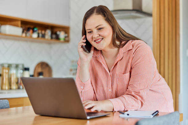 istock A smiling curvy businesswoman talking on a phone while working over a laptop from home. 1491276394