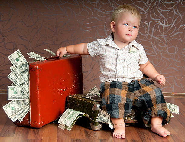 Cute little boy sitting on a suitcase with the money. stock photo