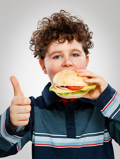 istock Boy eating hamburger showing OK sign 149127990