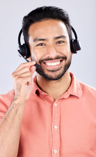 istock Portrait, call center and customer service with a man consultant in studio on a gray background. Contact us, crm or support and a happy male employee consulting with a headset for help or advice 1491283538