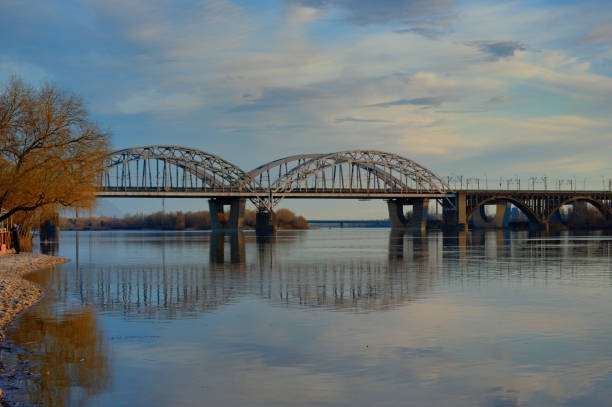 istock Scenic spring landscape Dnipro River in Kyiv during sunset. Bridge reflected in tranquil water of Dnieper River. Blue sky with white clouds in the background. Nature concept 1491283831