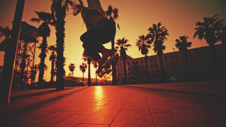 SUPER SLOW MOTION Back lit young woman roller skating on footpath at town square. Super slow motion of female skater is practicing stunt. She is in city during sunset.