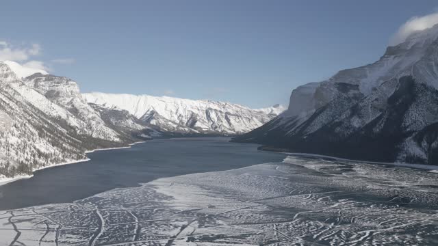 Aerial video flies over a frozen lake in Banff National Park in winter
