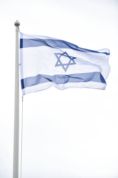 istock Israel state flag blown by the wind on a pole with clear sky on background 1491286153