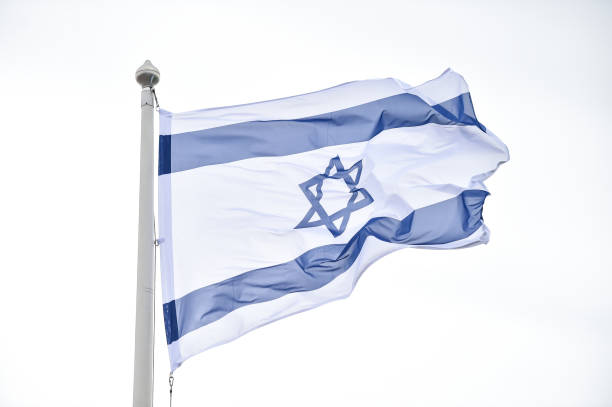 istock Israel state flag blown by the wind on a pole with clear sky on background 1491286155