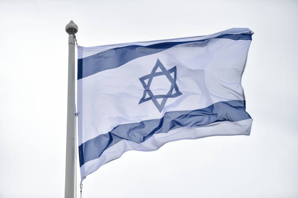 istock Israel state flag blown by the wind on a pole with clear sky on background 1491286159