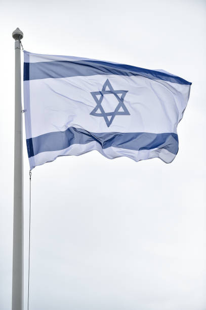 istock Israel state flag blown by the wind on a pole with clear sky on background 1491286173