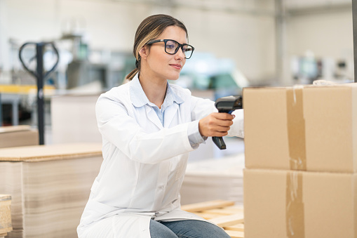 Female worker holding RFID scanner and scanning parcel barcode in delivery  warehouse