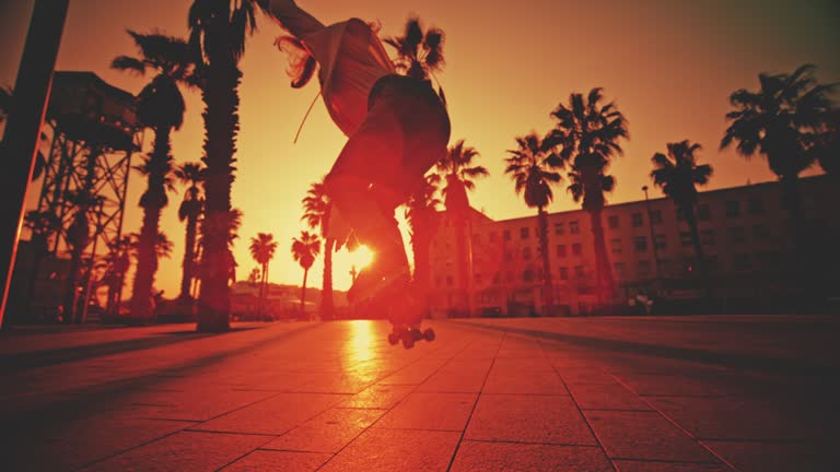 SUPER SLOW MOTION TIME WARPn of young woman spinning while roller skating on footpath. Female skater is practicing stunt at town square. She is in city during sunset.