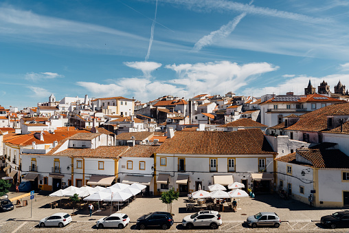Evora, Portugal - June 30, 2022: Cityscape of Evora with typical houses painted in white and ceramic tiled roofs. Square May 1th. Alentejo, Portugal