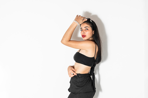 medium shot of a latina teenager posing on a white background with a hand on her head