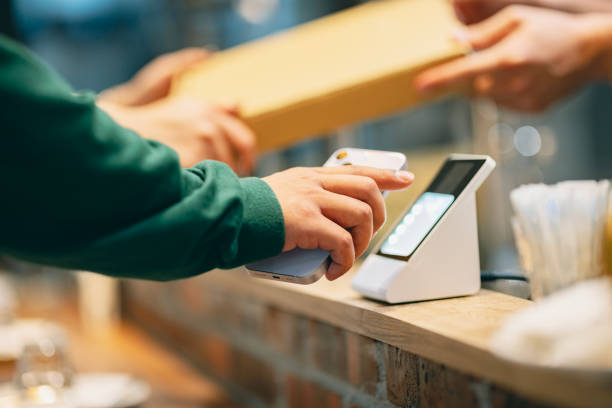By scanning the QR code using a card reader, the convenient concept of contactless payment is demonstrated, showcasing NFC (Near Field Communication) technology. Simply scanning the code allows for quick and easy completion of the payment process. en el restaurante, una mujer usa su teléfono inteligente para hacer un pago con el cajero. ella escanea el código qr usando un lector de tarjetas para completar un conveniente pago sin contacto. al mismo tiempo, el cajero entrega la pizza comprada al cli