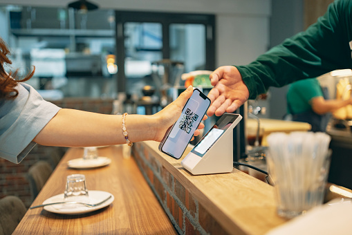 By using a device to scan a QR code and make a payment, the transaction is completed quickly and conveniently through contactless payment. This scene showcases the concept of NFC technology, where a simple scan enables seamless payment.