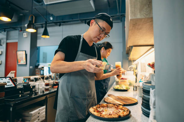 Two Asian restaurant staff members are working in the kitchen, collaborating to create delicious meals.
