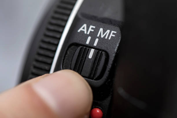 istock Fingers selecting MF manual focus mode on a professional camera lens. man putting MF manual focus mode on lens photos. Man selecting in Close up of manual focus MF switch on camera lens 1491291193