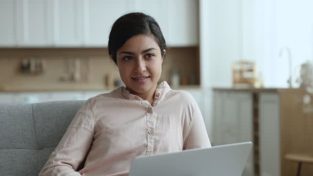 Thoughtful freelancer Indian woman working at home use notebook