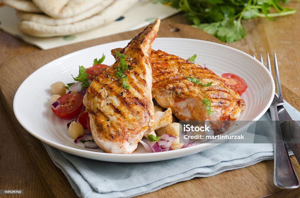 Chicken with salad Harissa chicken with chickpea and tomato salad Barbecue Chicken Stock Photo