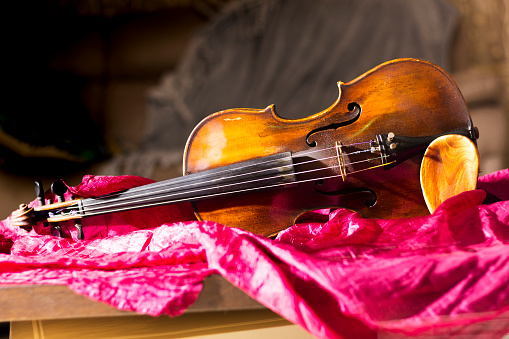 An old gypsy violin on a red coverlet.