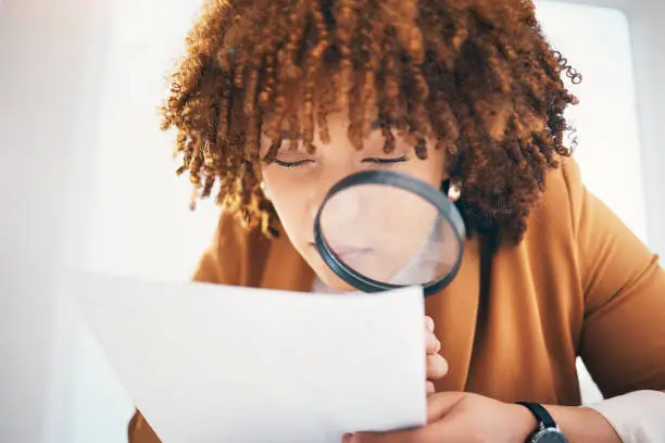 Photo of Black woman, magnifying glass and office for inspection with documents, hr recruitment and focus. Human resources expert, manager and paper research for hiring, opportunity or job for future employee