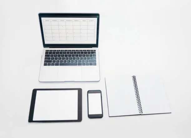 Photo of Laptop, tablet and phone mockup with notebook above for schedule planning, advertising or marketing. Computer, touchscreen and smartphone screen display for calendar reminder or organized workspace