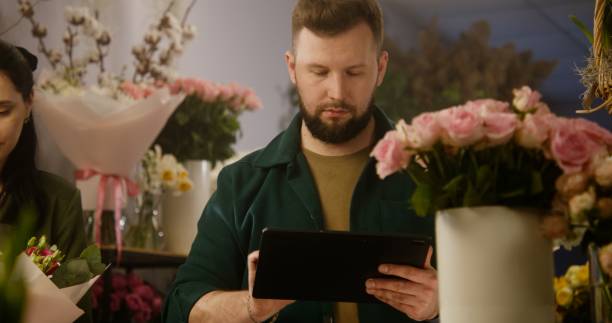 istock Male florist takes customer order online using digital tablet 1491299104