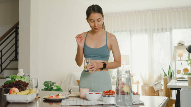 istock Young Asian athletic woman using blender and preparing fresh fruit smoothie at home. Healthy food. 1491299387