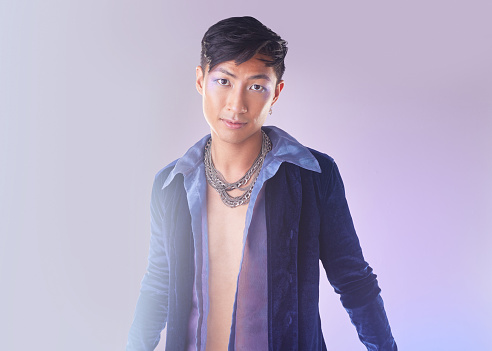 Art, makeup and lgbt portrait of man in Indonesia, confidence isolated on purple background. Style, aesthetic and fashion model with beauty in studio, creative non binary and gender neutral design.