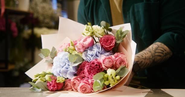 istock Male florist wraps bouquet, uses wrapping paper 1491301770